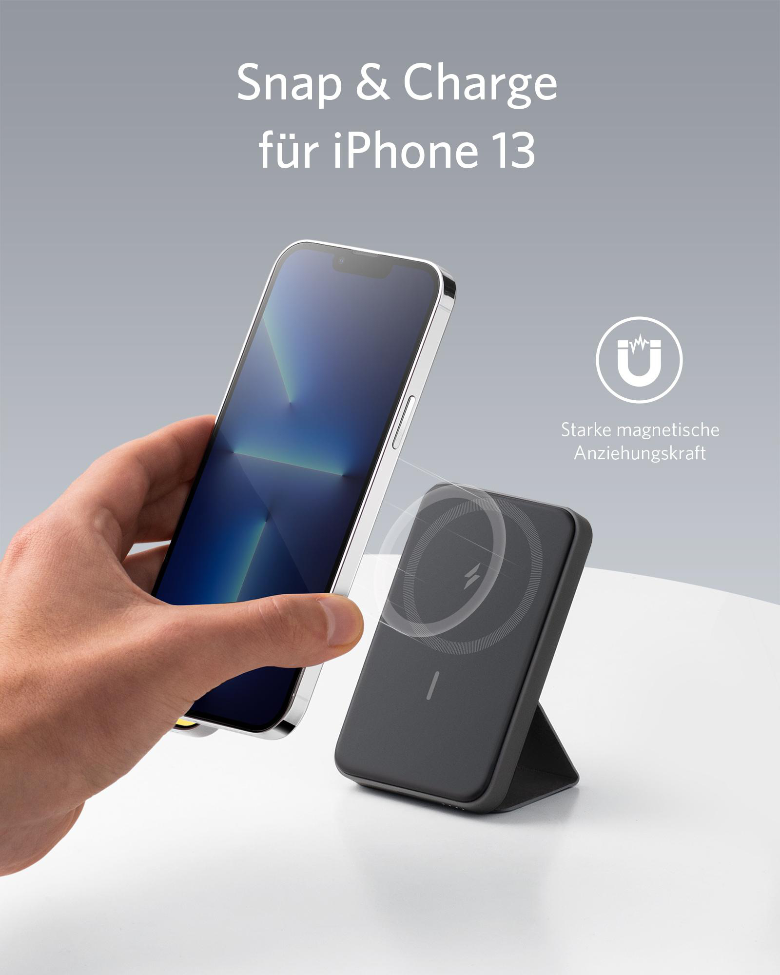 Hand, die ein Telefon hält, das drahtlos aufgeladen wird. Eine schwarze Ladestation mit einem iPhone 13 sind im Bild.