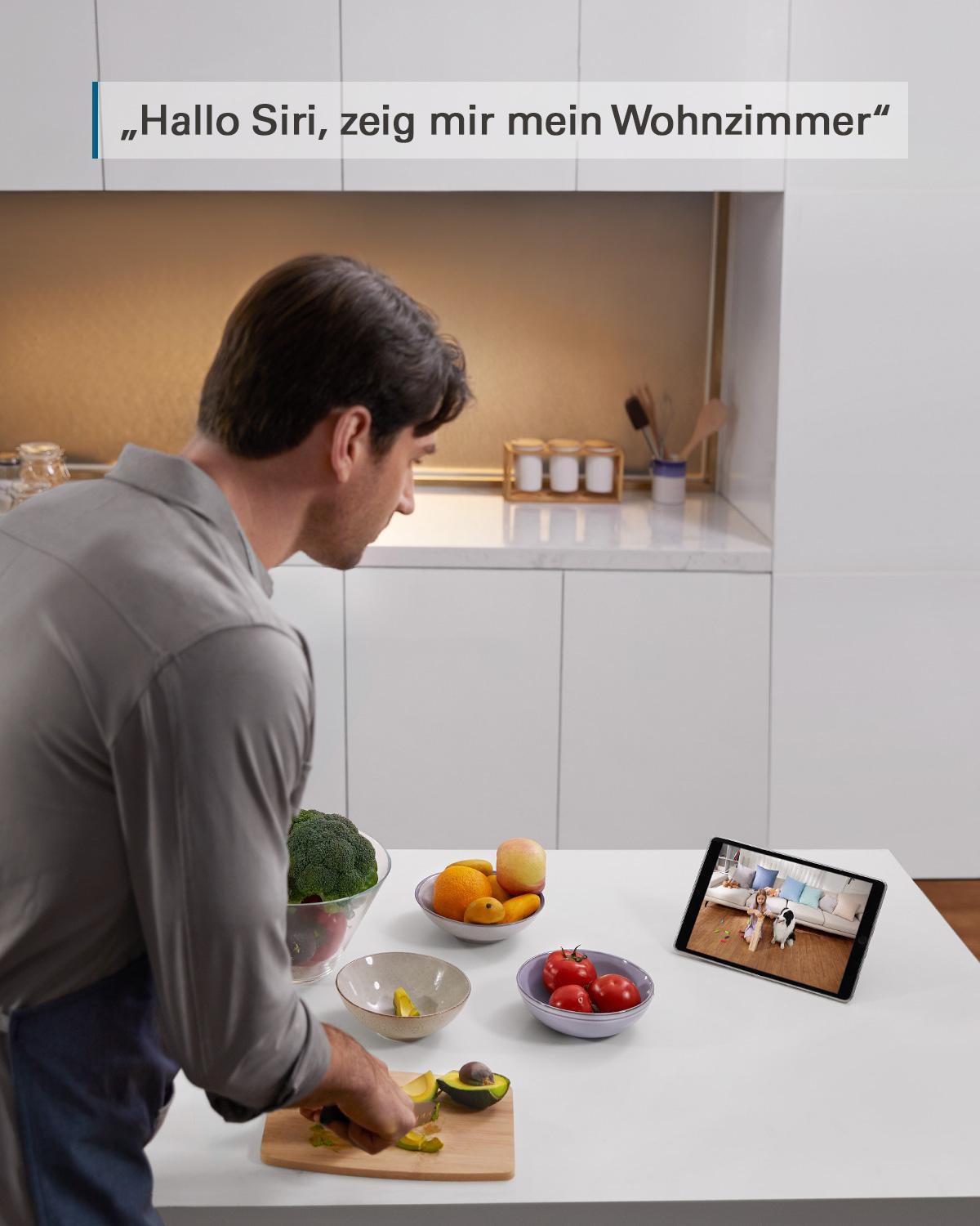 Mann in der Küche, der ein Tablet mit Smart Home-Oberfläche benutzt. Obst und Gemüse auf dem Tisch.
