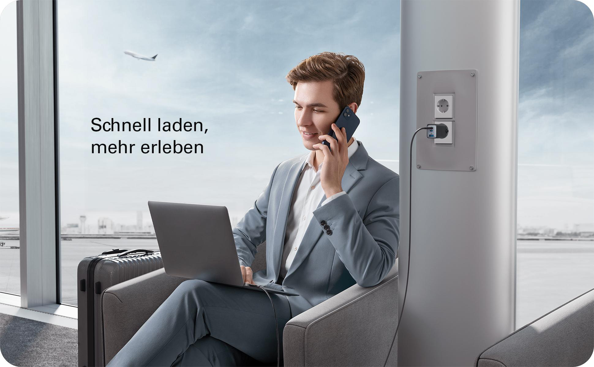 Mann im Anzug telefoniert, lädt Laptop. Flugzeugfenster im Hintergrund. Text: Schnell laden, mehr erleben.