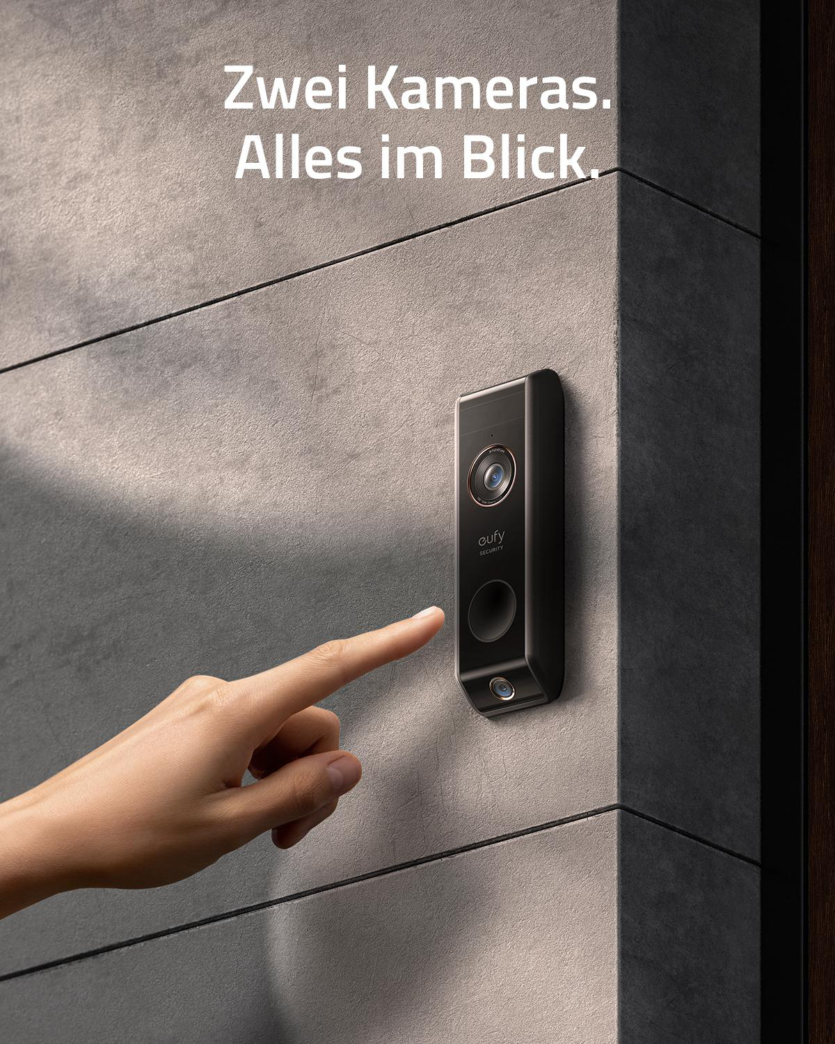 Ein Finger berührt eine Türklingelkamera an einer grauen Wand.