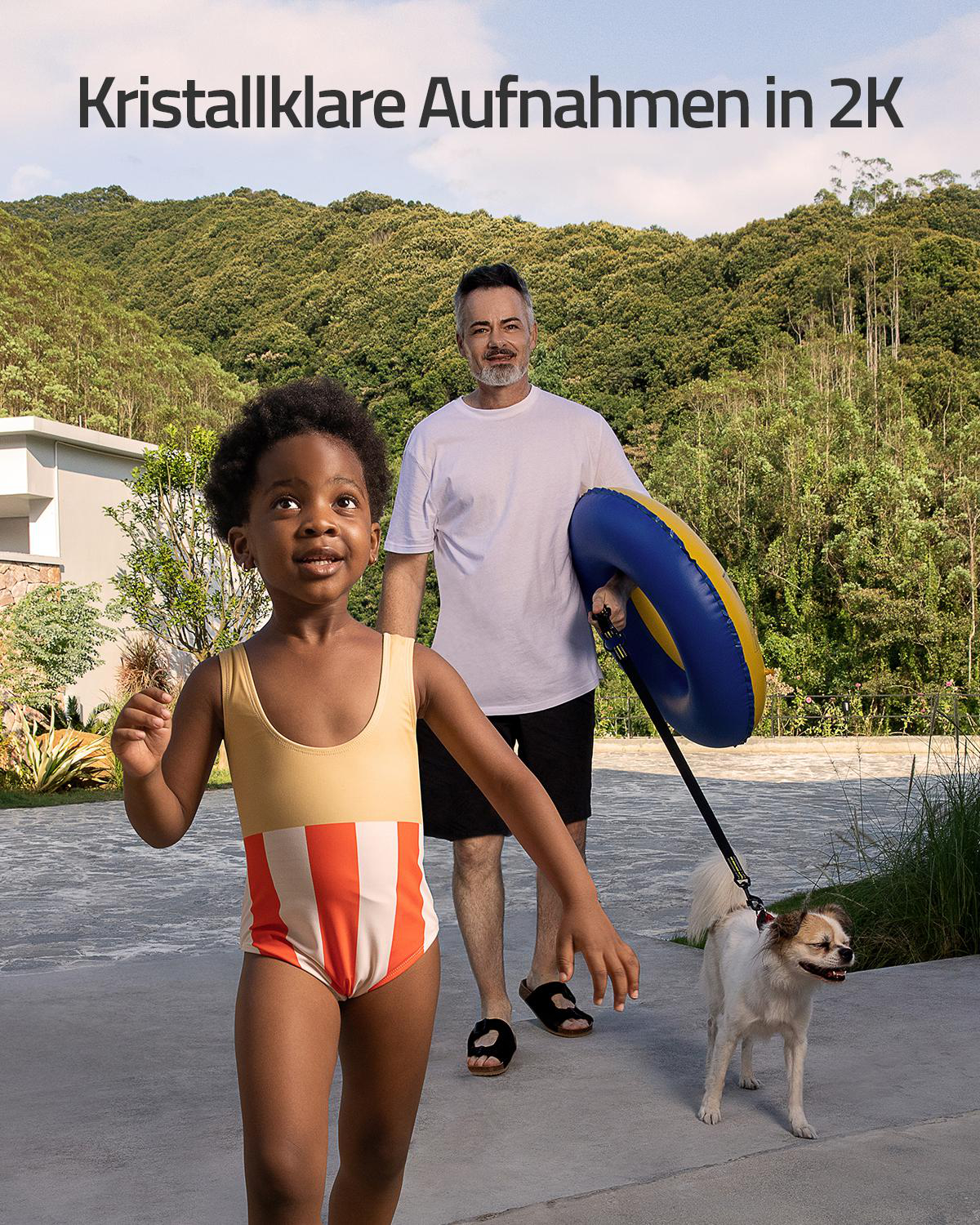 Ein Kind in Badehose, ein Mann mit Schwimmring und ein Hund gehen auf einem Weg.