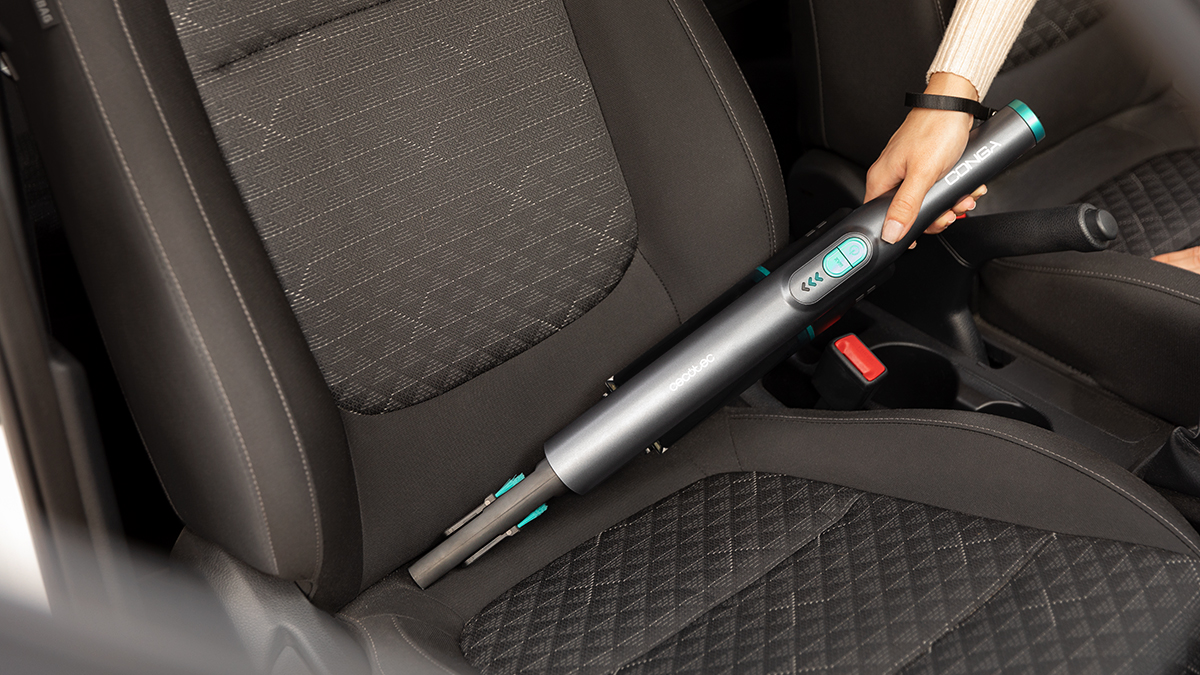 Una persona está usando una aspiradora de mano en un coche.