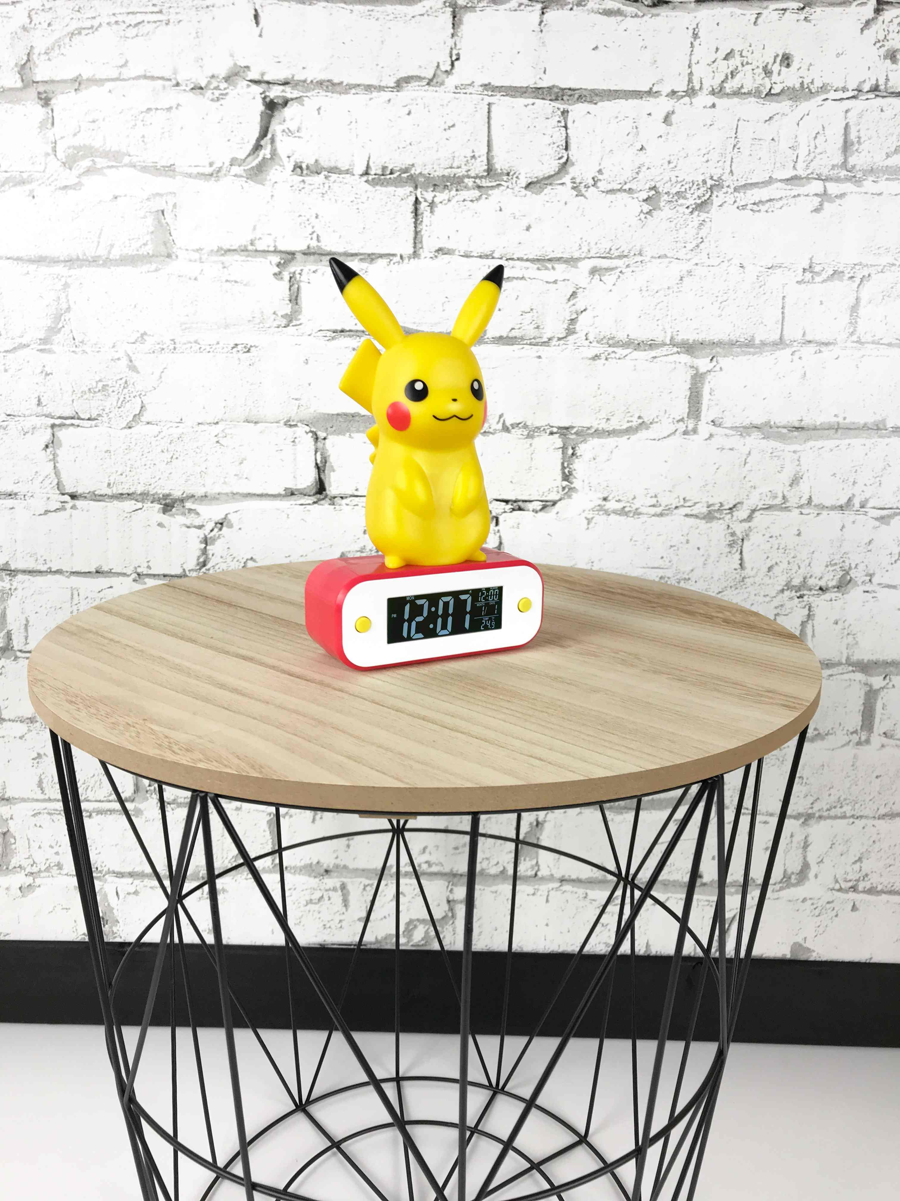 Sveglia Pikachu su tavolo a cestello. Sfondo: muro di mattoni bianchi.
