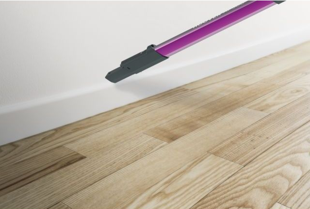 Tête d'aspirateur nettoyant le bord du mur et le parquet.