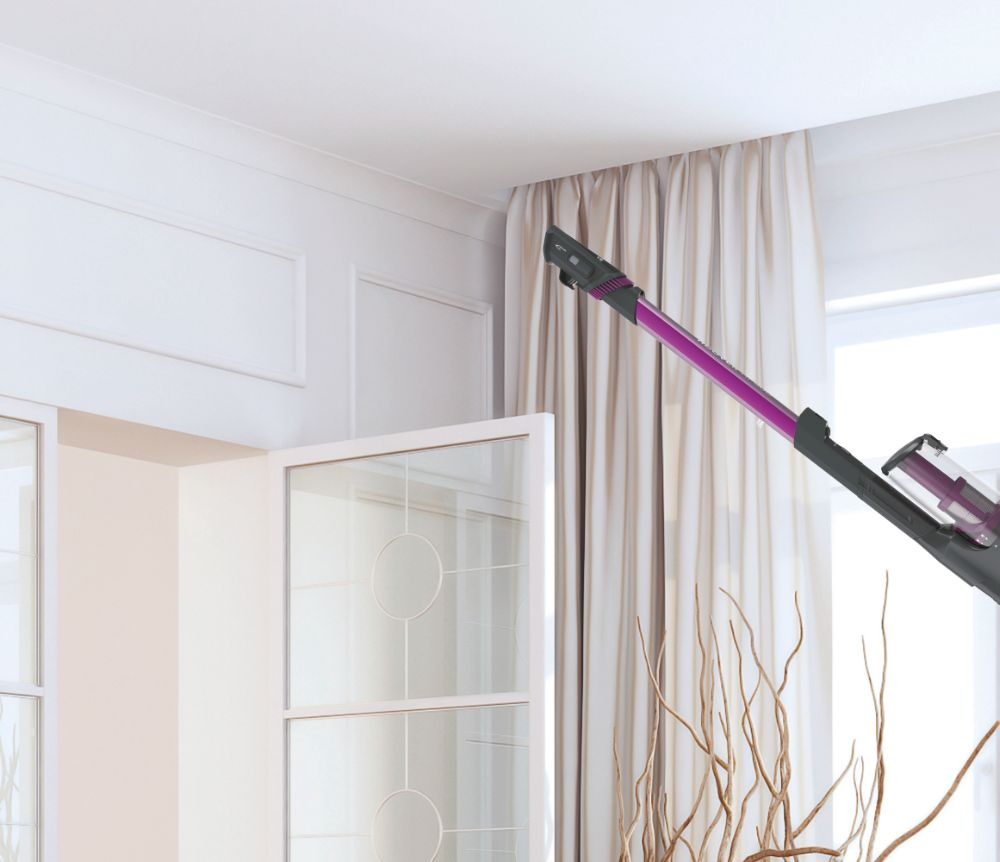 Un aspirateur nettoyant une pièce, avec un rideau et une fenêtre.