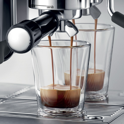 Dos vasos llenándose de café de una máquina de espresso.