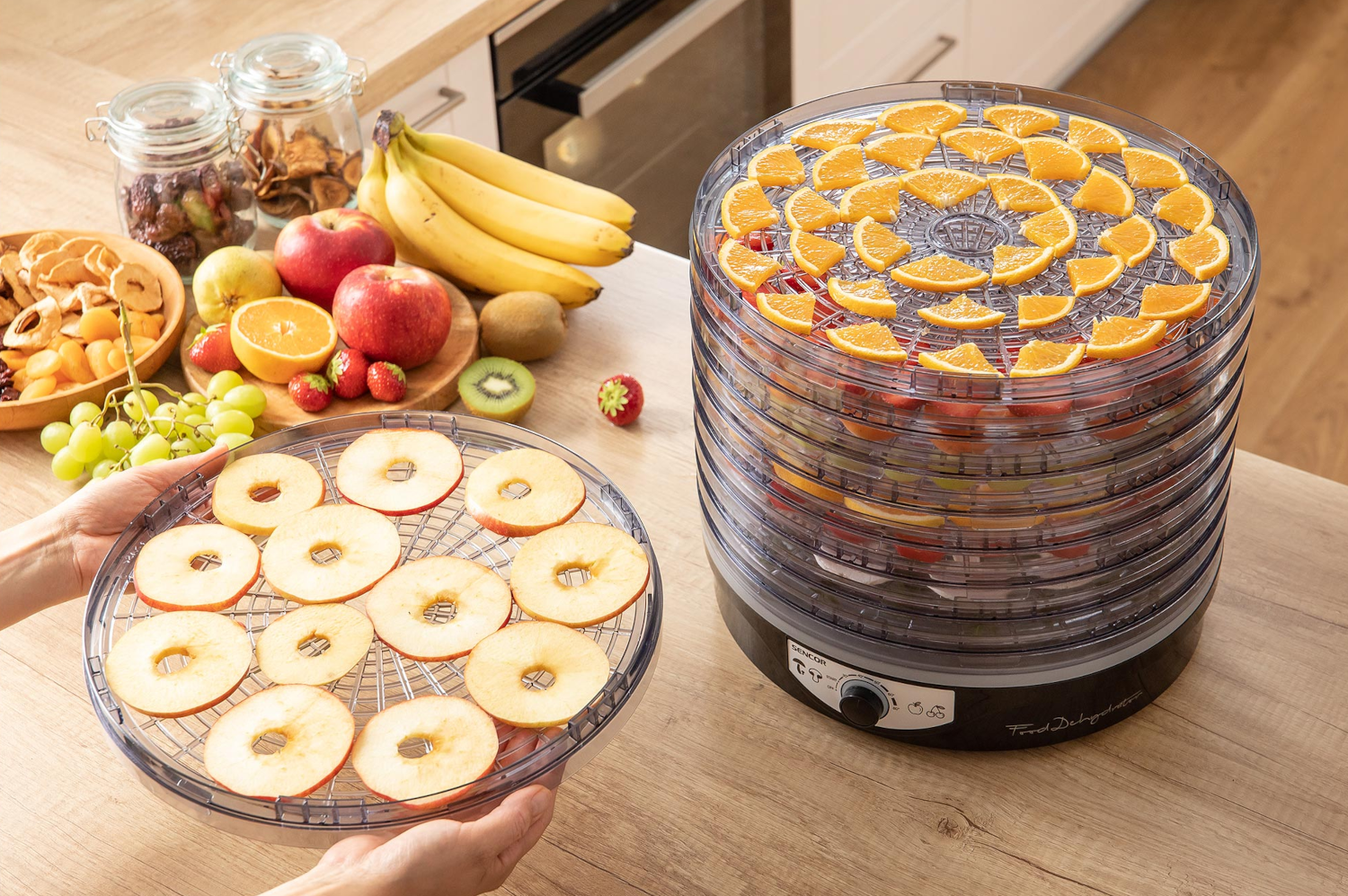 Étel-dehidratáló szeletelt narancsokkal és almákkal. Egy tál almával van előtte.