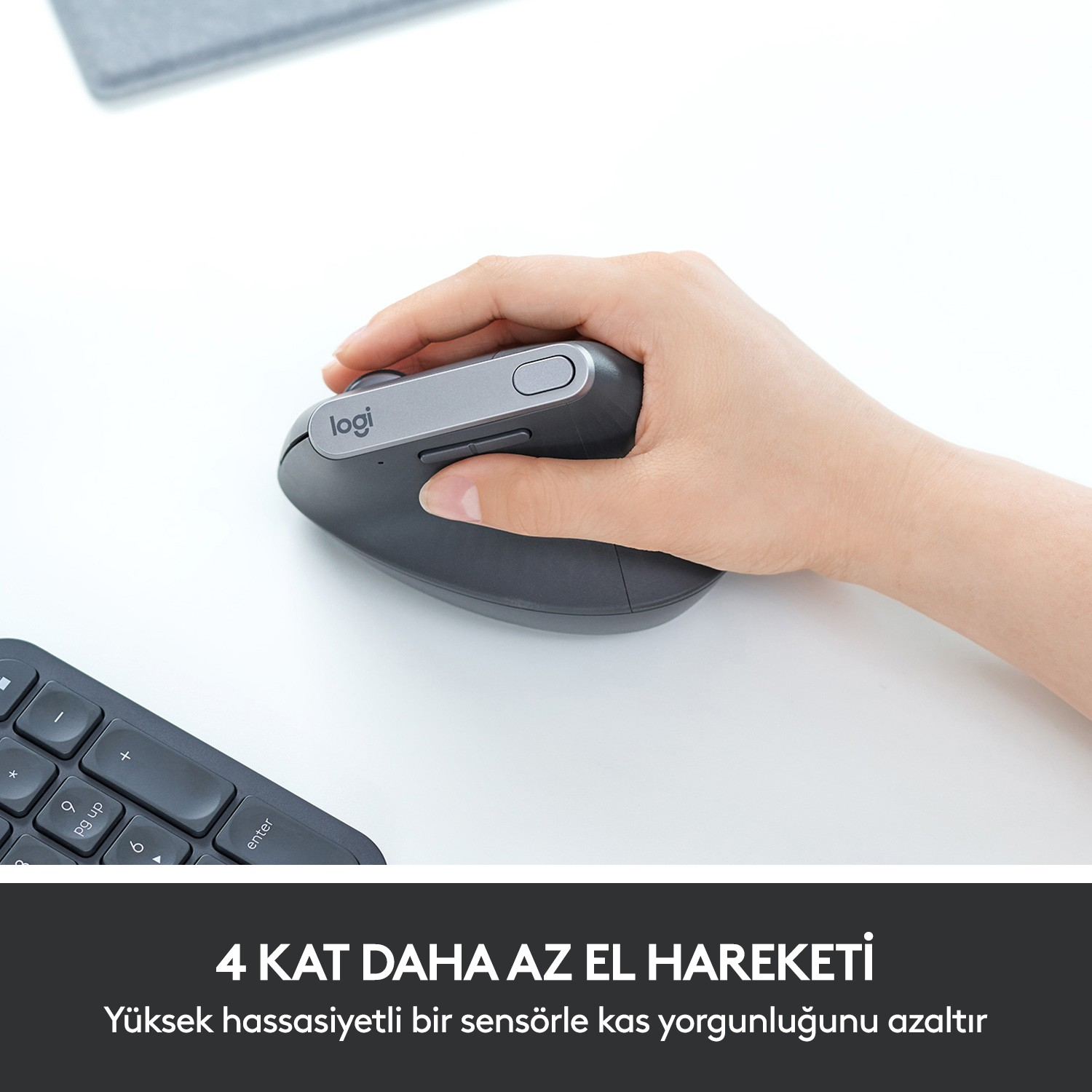 Bir el, beyaz bir masada gri bir ergonomik fare tutuyor, köşede bir klavye var.