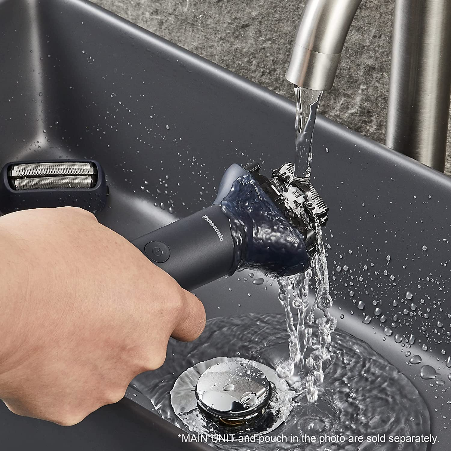 Una mano sosteniendo una afeitadora negra Panasonic bajo agua corriente en un lavabo.