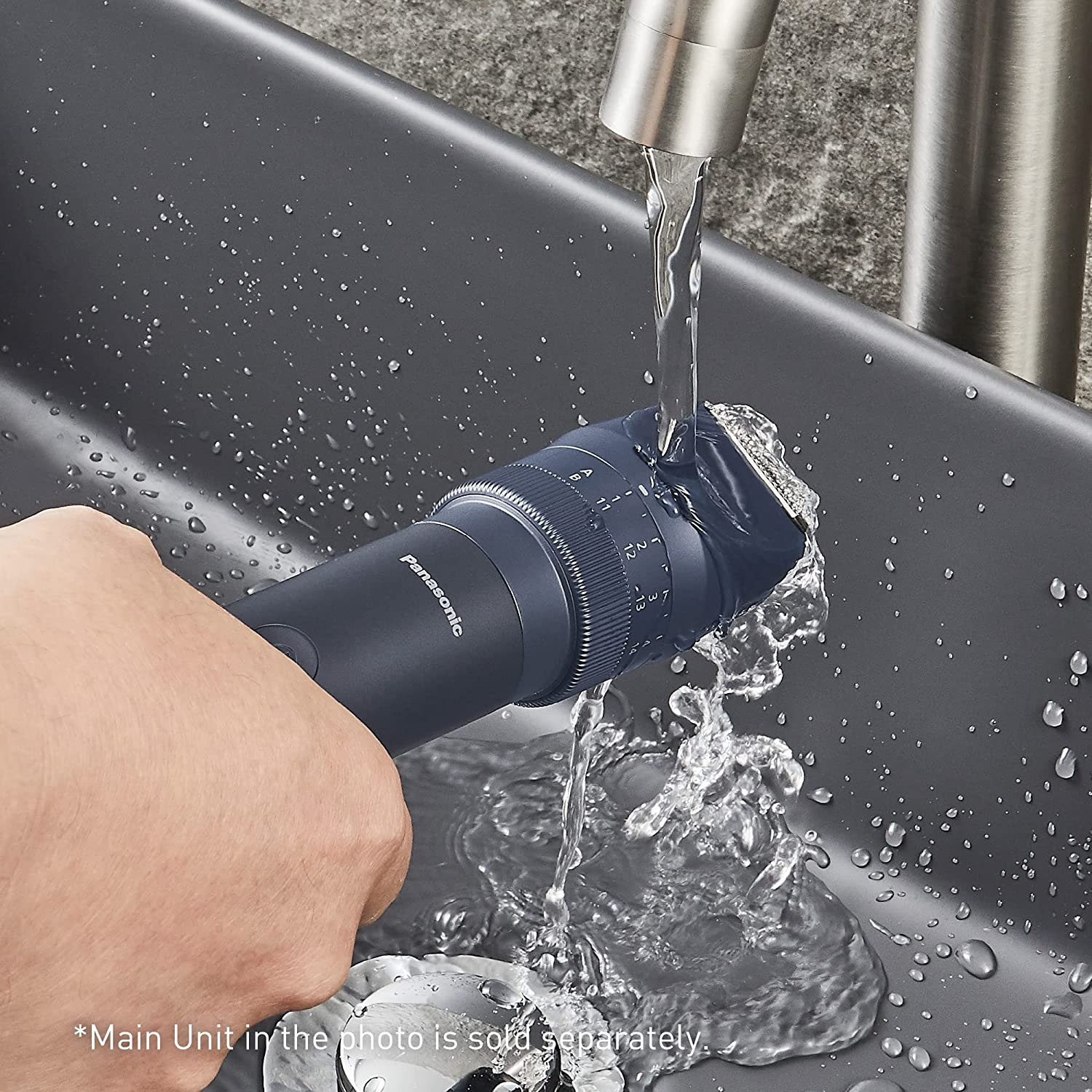 Persona lavando una afeitadora eléctrica azul oscuro bajo agua corriente.