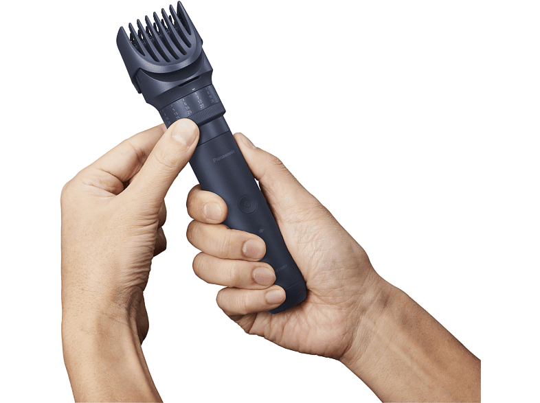 Manos sosteniendo recortadora de barba negra, mostrando dial y peine.