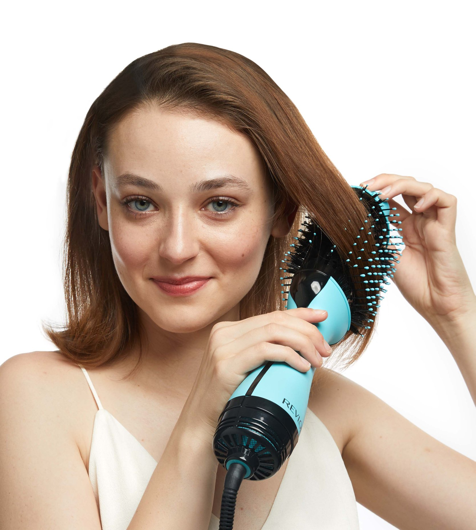 Una donna usa una spazzola asciugacapelli Revlon verde acqua e nera sui suoi capelli castani.