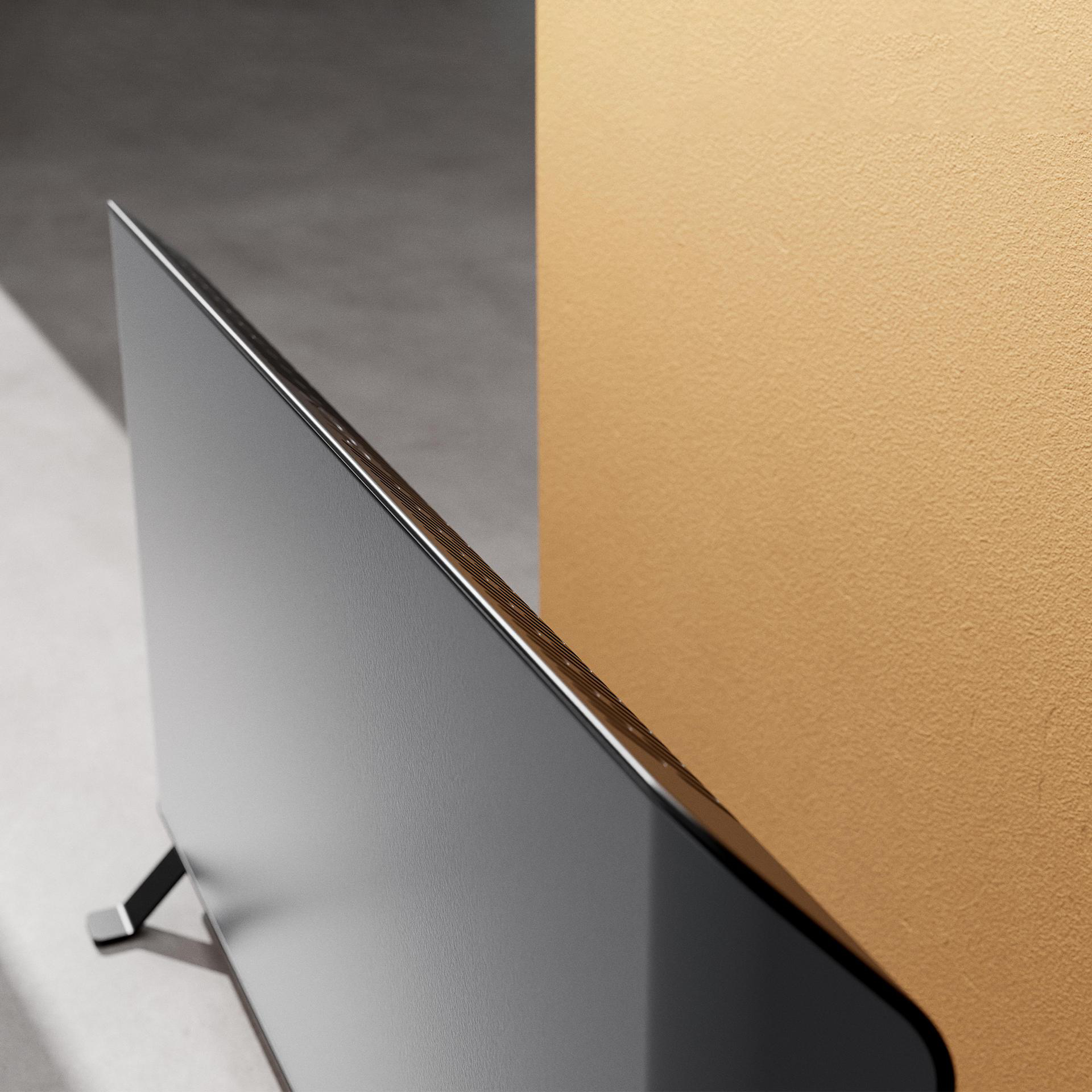 Moderner Fernseher vor einer orangefarbenen Wand, zeigt einen schwarzen Bildschirm und einen Ständer.