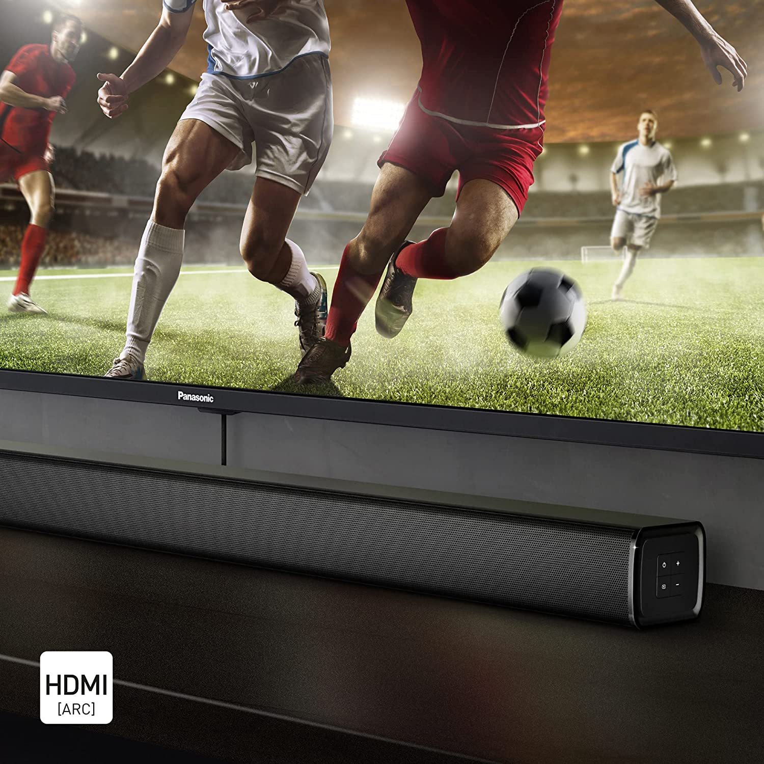 Una barra de sonido frente a un televisor con un partido de fútbol.