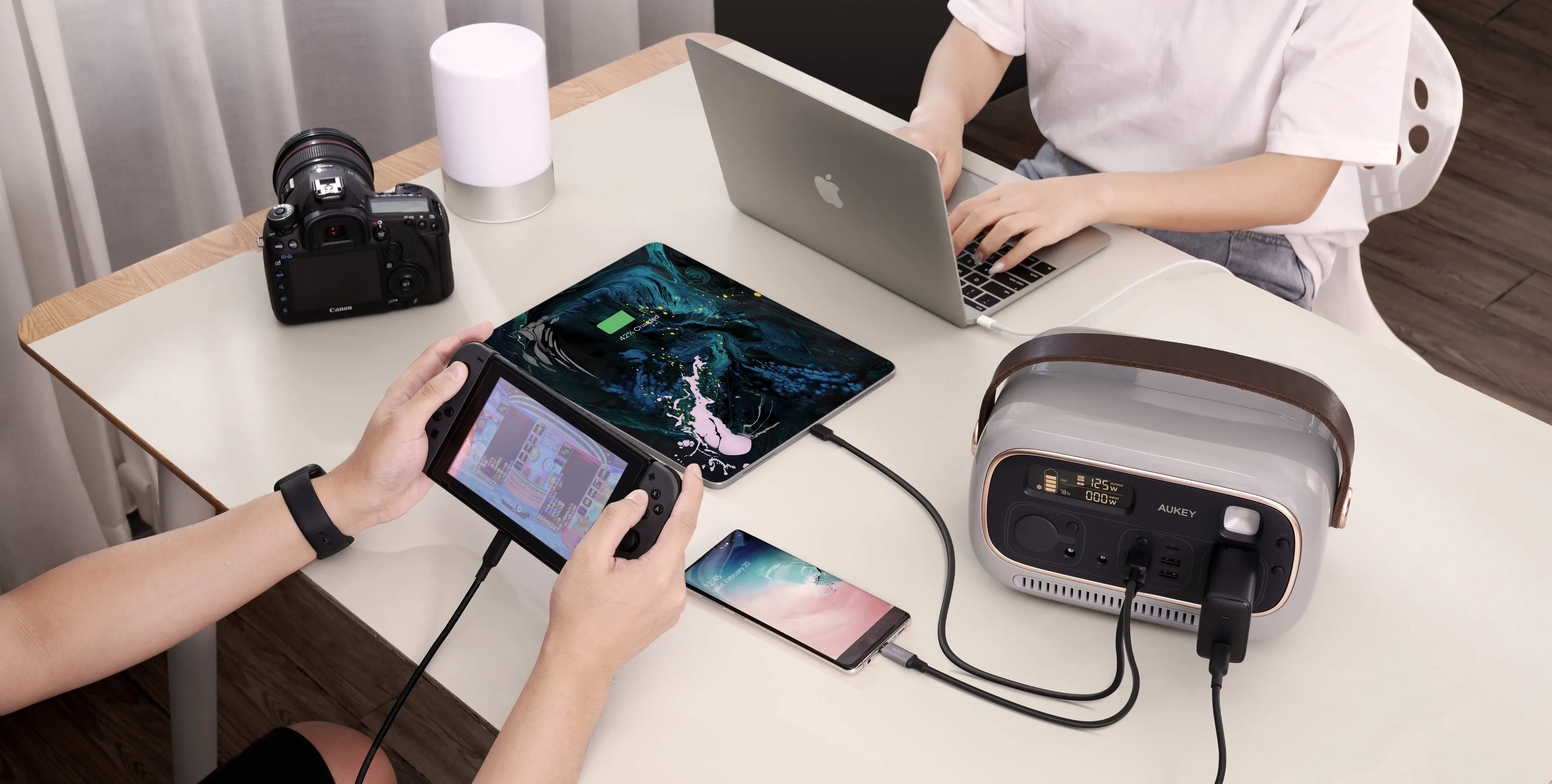 Persone che usano dispositivi elettronici: laptop, tablet, telefono, console di gioco e stazione di alimentazione.