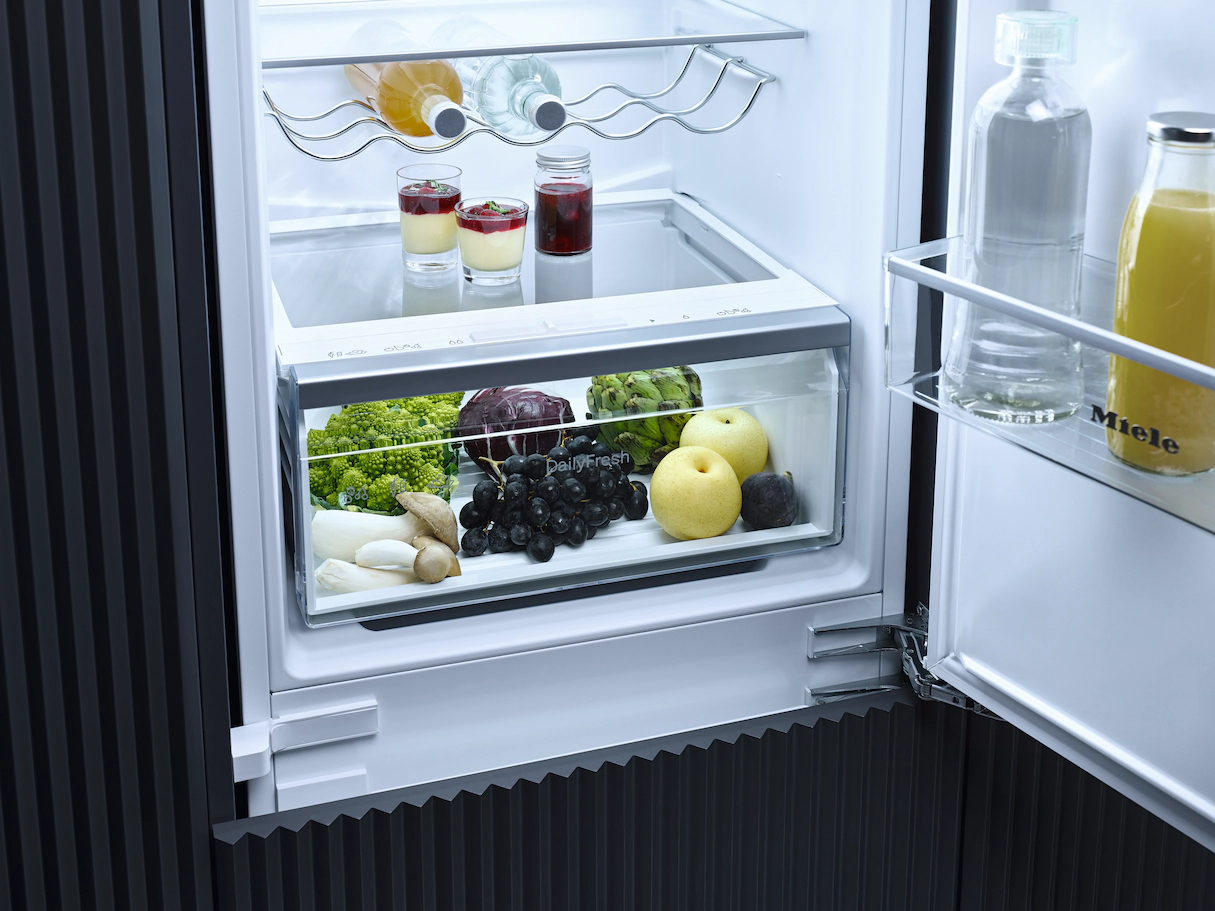Kühlschrankinnenraum mit frischen Produkten: Obst, Gemüse und Flaschengetränke.