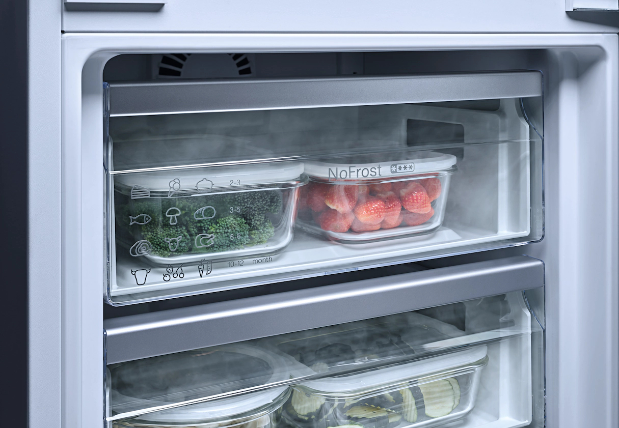 Ein geöffneter Kühlschrank mit zwei transparenten Behältern, die mit Lebensmitteln gefüllt sind.