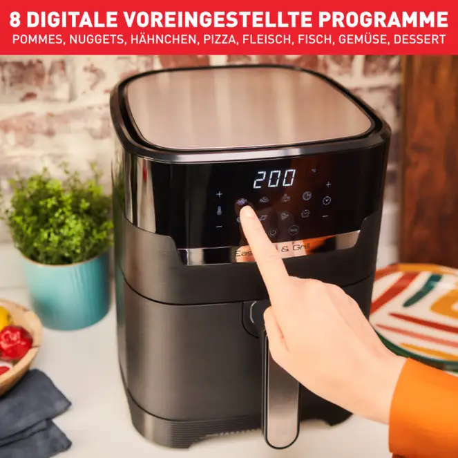 Eine Hand drückt einen Knopf an einer Heißluftfritteuse mit Touchscreen.