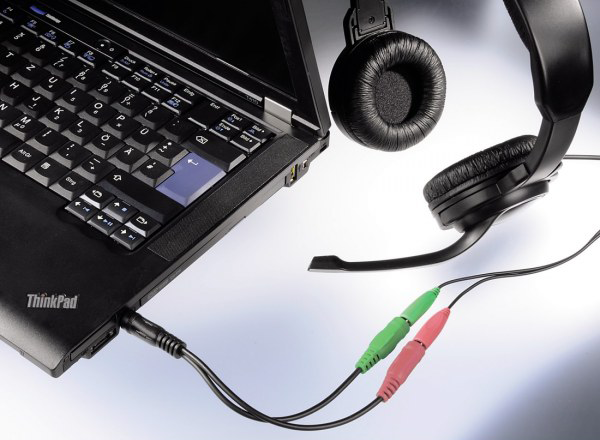 Egy laptop egy mikrofonos fejhallgatóhoz csatlakoztatva, kábelekkel.