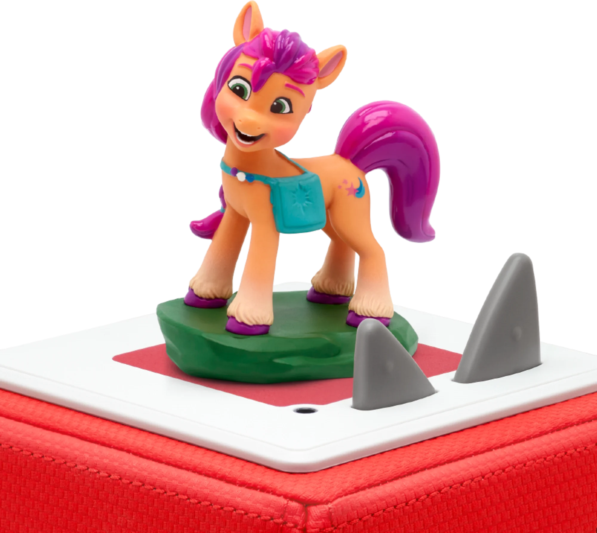 Eine Spielzeug-Ponyfigur mit rosa Mähne und Schweif, die auf einer grünen Plattform mit Haifischflossen steht.
