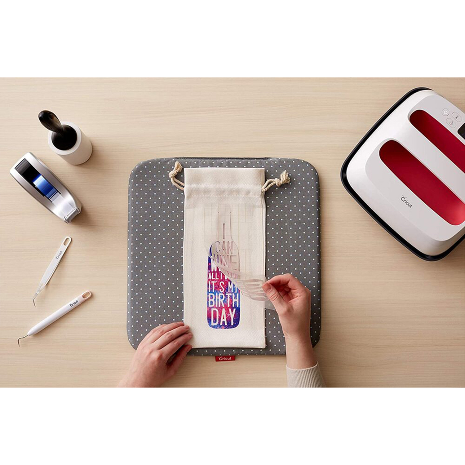 Mani che tengono uno stencil su una borsa. Macchina e strumenti Cricut.