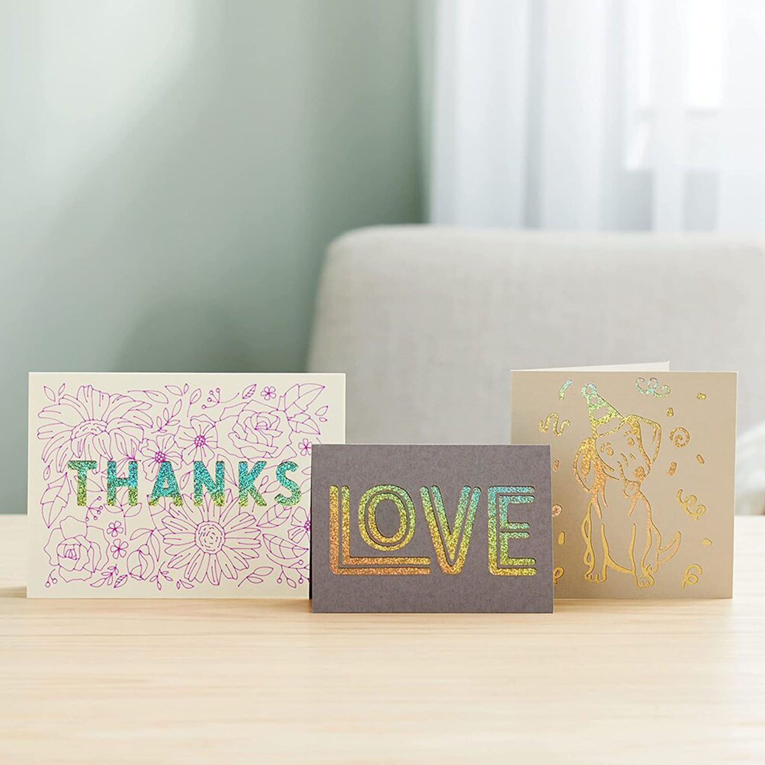Tre biglietti di auguri con lettere ritagliate e disegni floreali, vari colori.