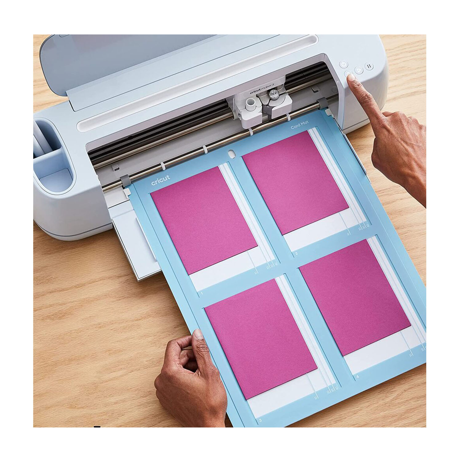 Una macchina Cricut con un tappetino da taglio. La mano di una persona preme un pulsante sulla macchina.