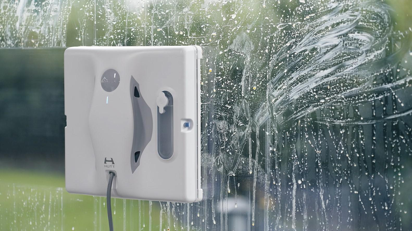 Fensterputzer an einem Fenster, Reinigung mit weißer Flüssigkeit.