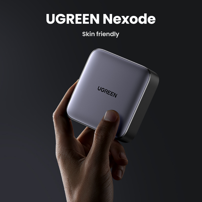 Una mano che tiene un caricabatterie UGREEN Nexode grigio su sfondo scuro.