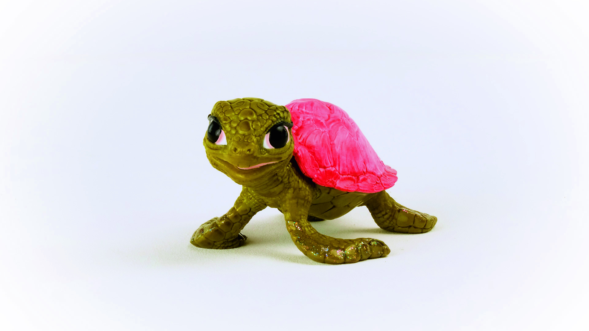 Ein grünes Schildkrötenspielzeug mit rotem Panzer. Es befindet sich auf weißem Hintergrund und schaut nach vorne.