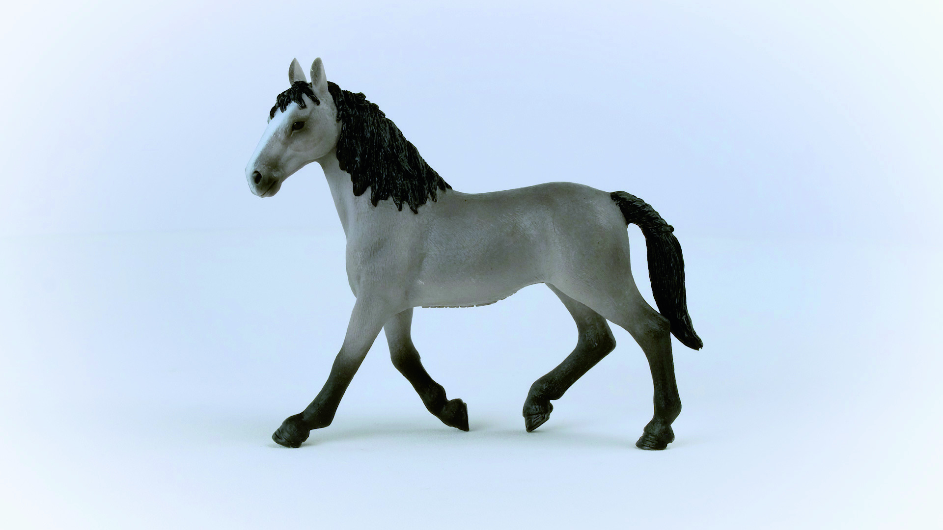 Eine graue Pferdfigur auf einer weißen Oberfläche.