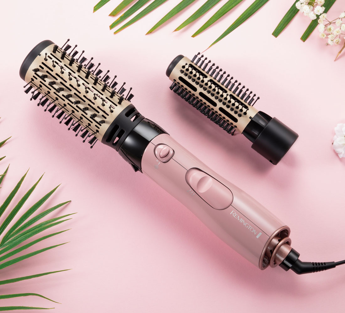 Zwei Haarbürsten mit rosa Hintergrund und grünen Blättern.