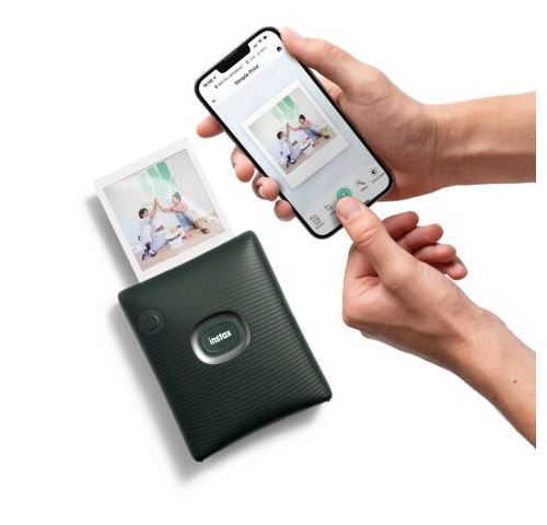 Una persona imprime una foto desde un teléfono inteligente usando una impresora Instax portátil.