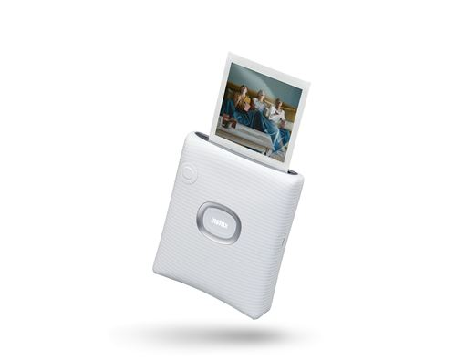 Impresora Instax blanca con impresión fotográfica. Imagen muestra personas. Fondo blanco.