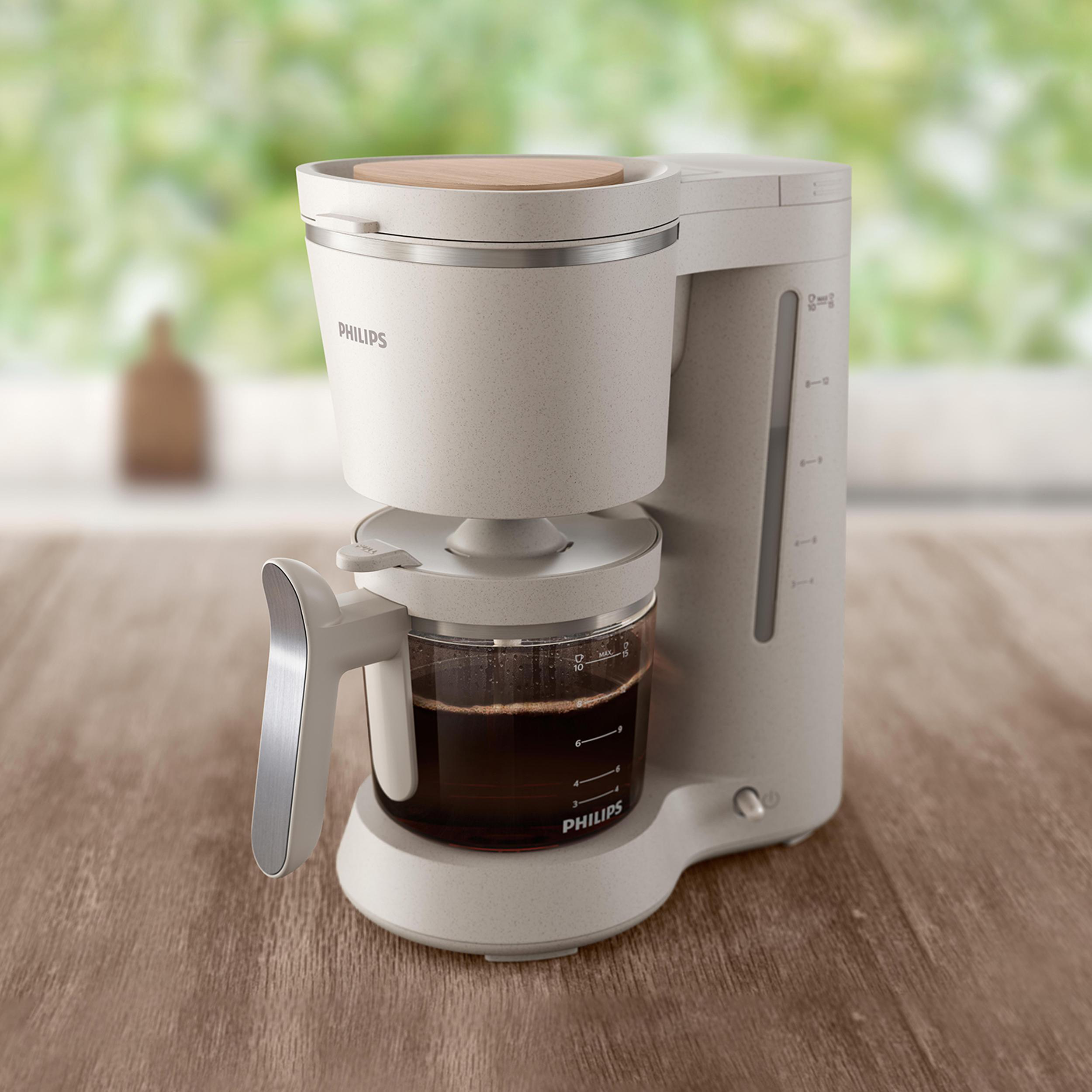 Eine weiße Philips-Kaffeemaschine auf einer Holzoberfläche. Ein verschwommener Hintergrund ist sichtbar.
