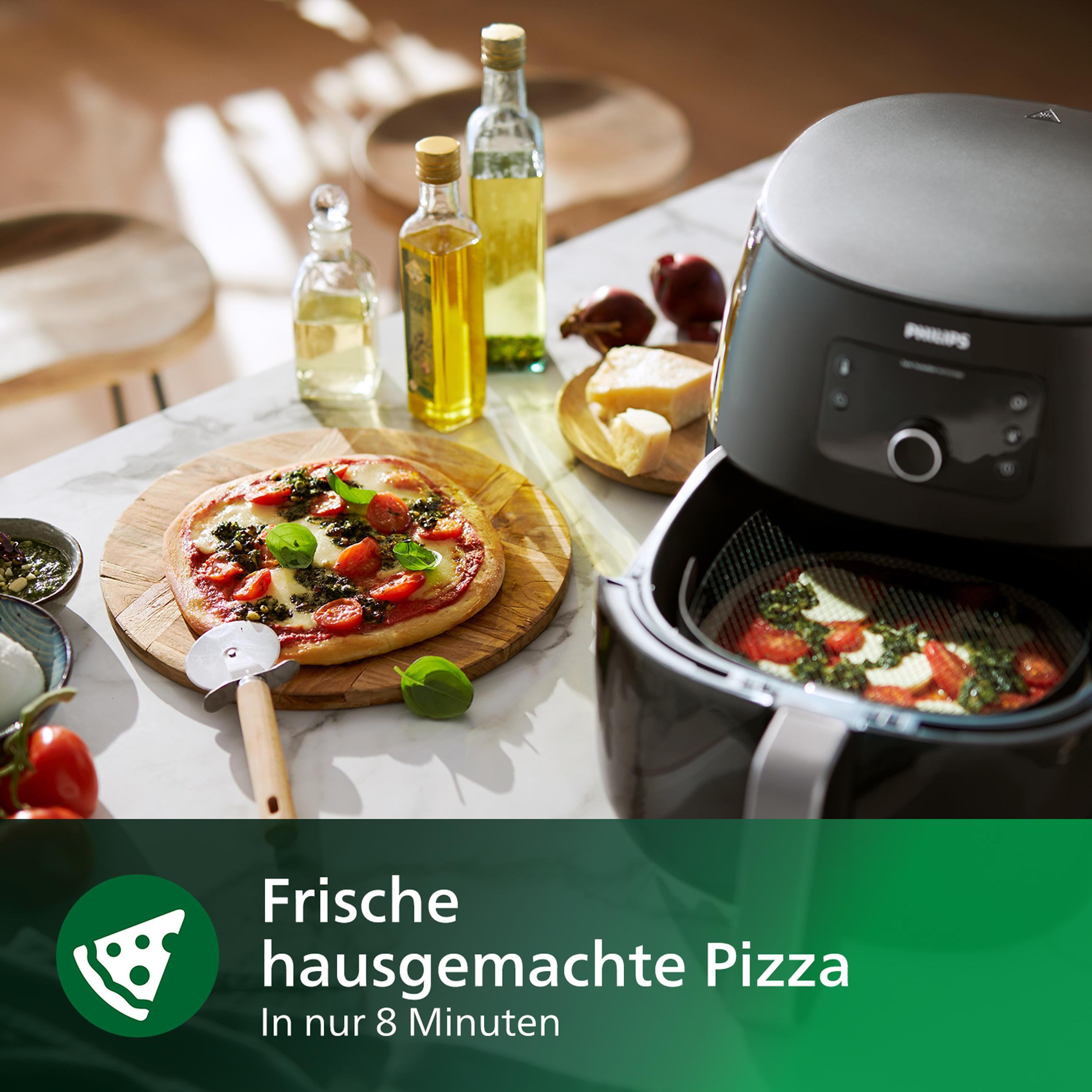 Pizza auf einem Holzbrett mit Zutaten drumherum. Eine Heißluftfritteuse ist geöffnet, mit Pizza darin.