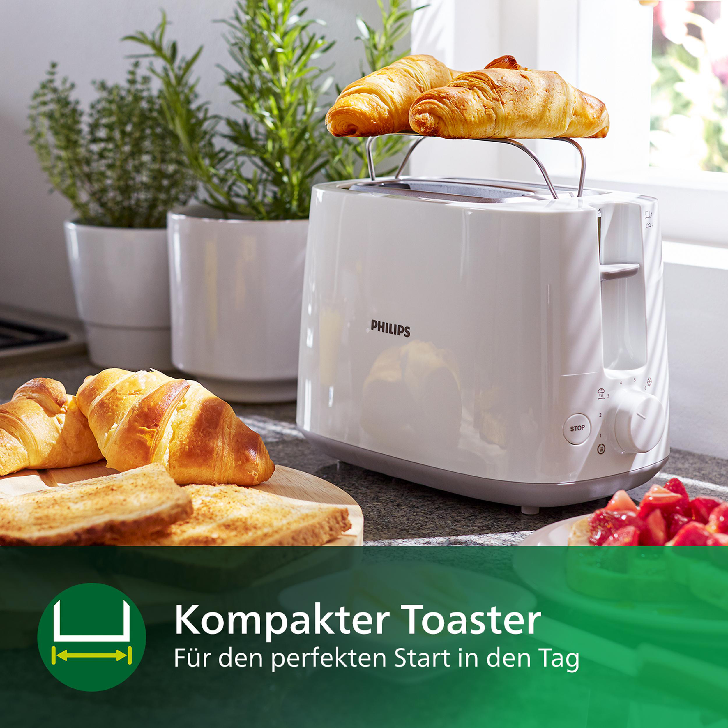 Weißer Toaster mit Croissants, Toast und einem Tablett mit Erdbeeren, in einer Küchenumgebung.