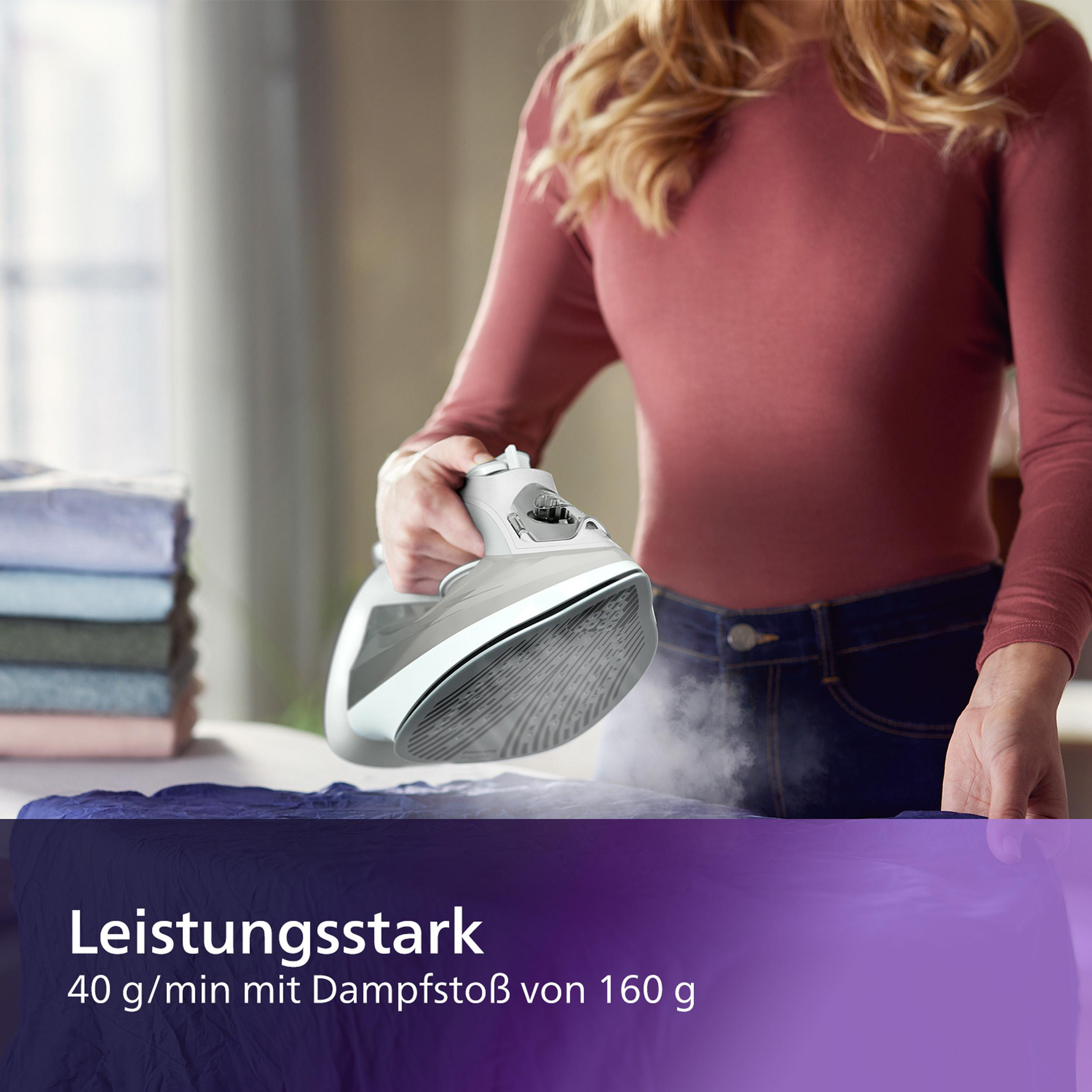 Frau bügelt blauen Stoff mit Dampf, mit einem weißen und grauen Bügeleisen.