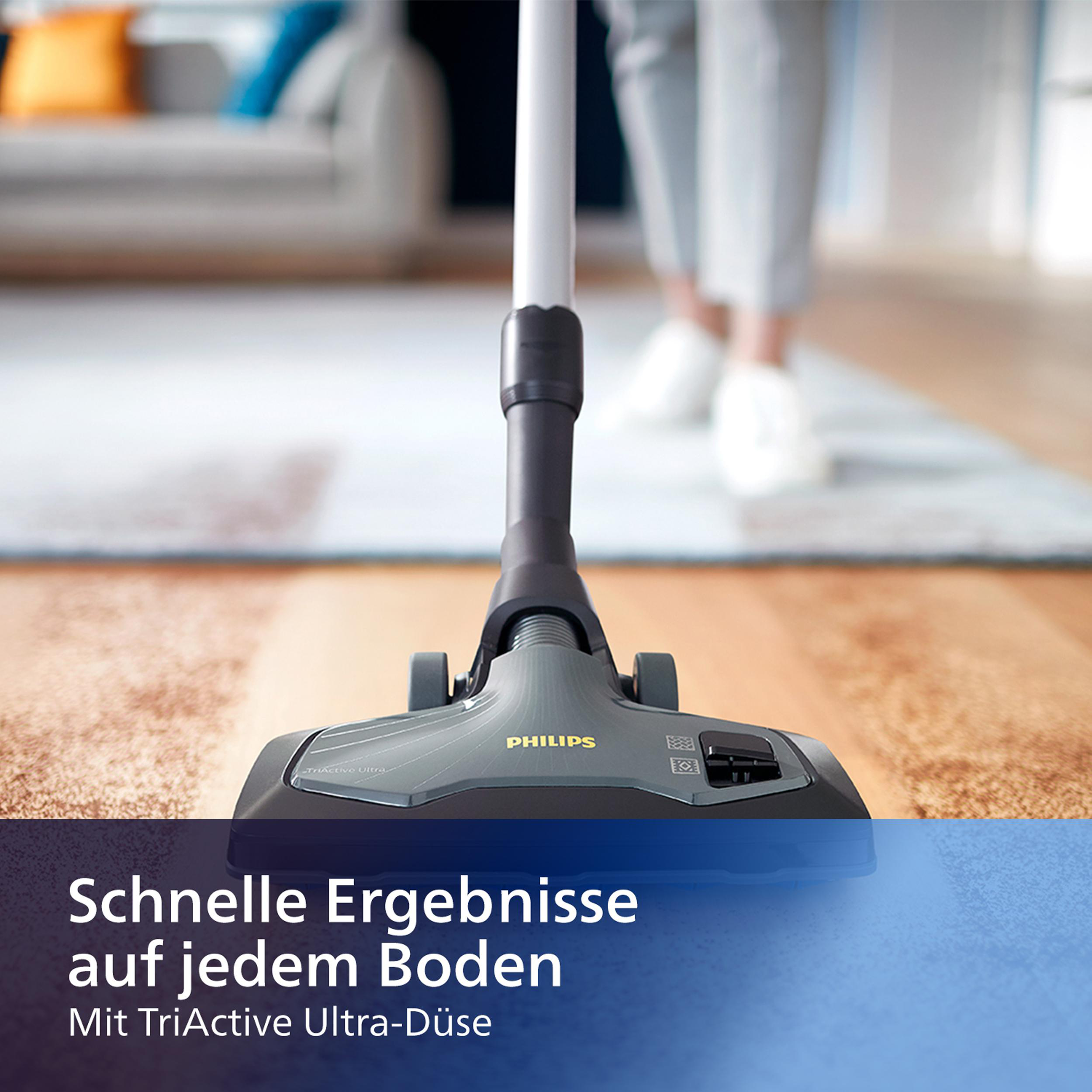 Staubsaugerkopf auf einem Teppich, mit einer Person im Hintergrund.