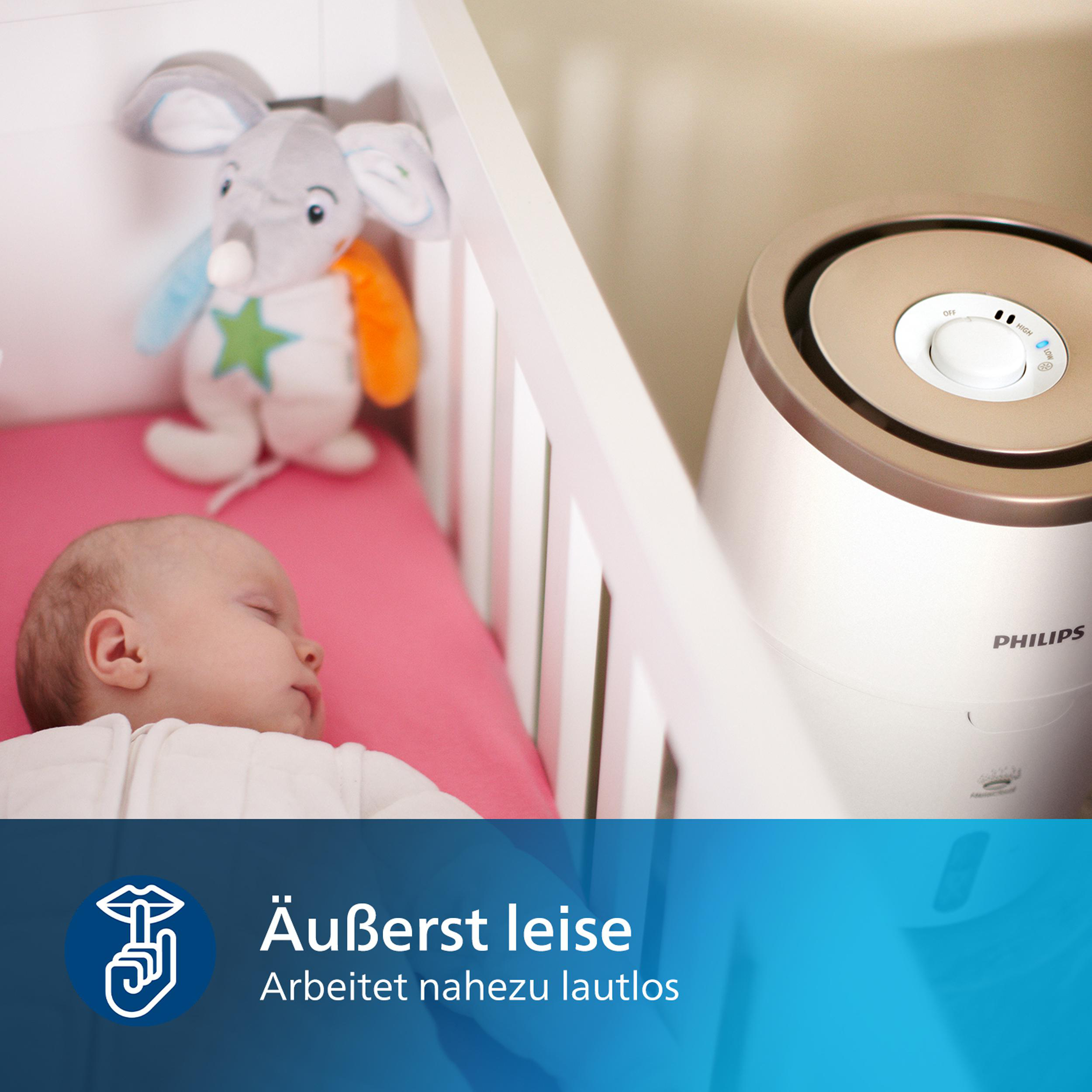 Ein Baby schläft im Kinderbett. Ein Stofftier und ein Luftbefeuchter sind im Bild.