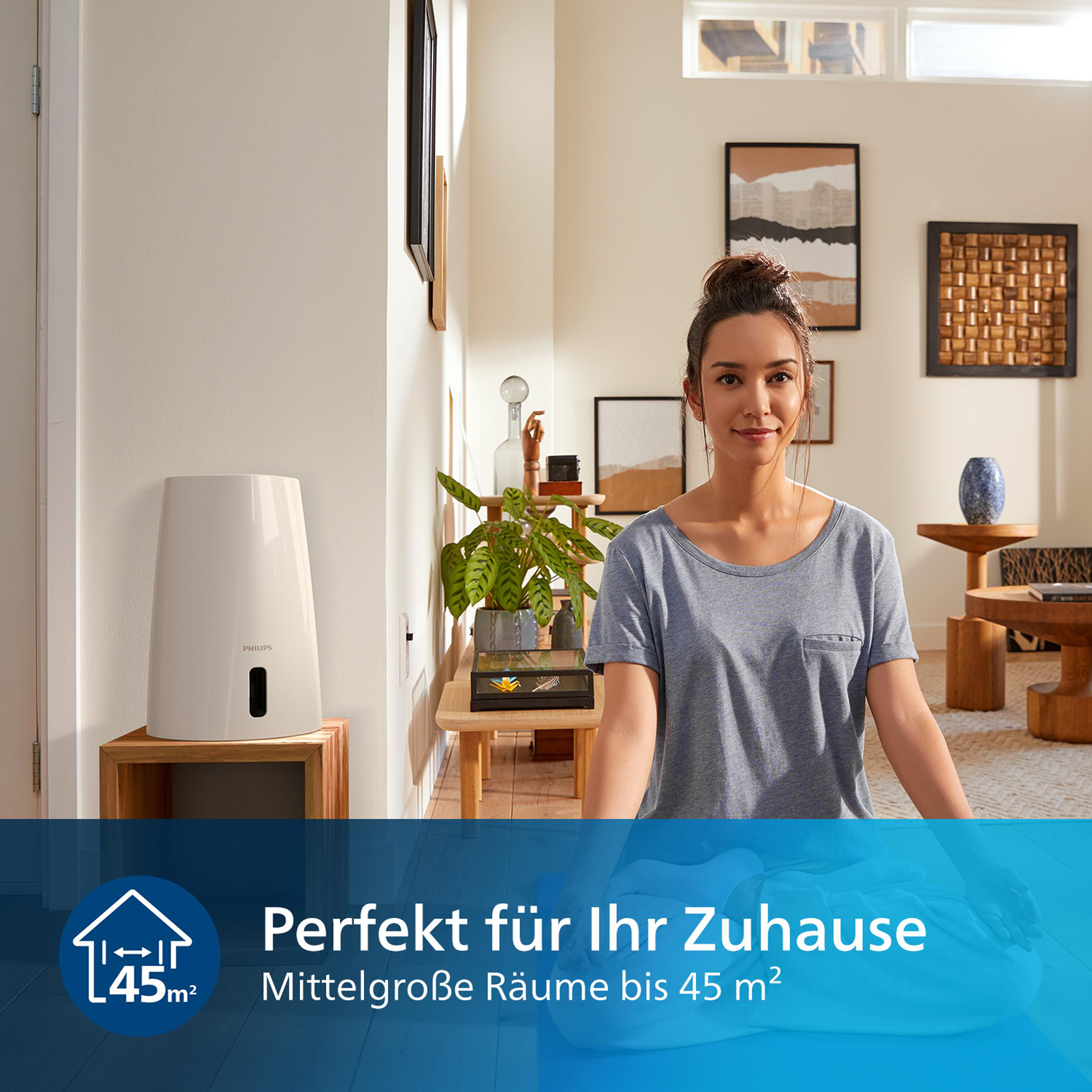 Frau in einem Wohnzimmer, die in der Nähe eines weißen Luftbefeuchters steht, mit einem blauen Banner unten.