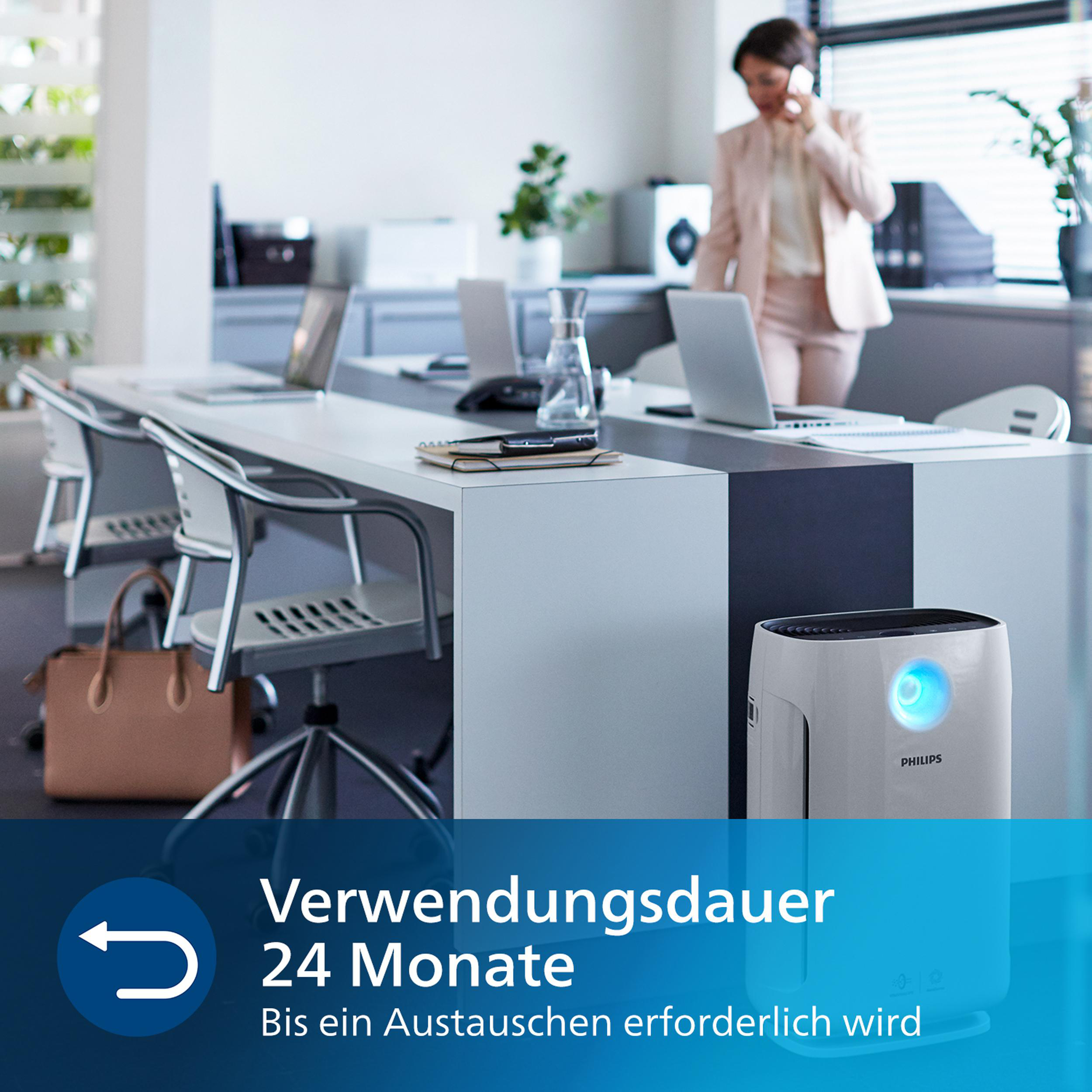 Eine Frau in einem rosa Blazer und einem weißen Hemd benutzt ein Telefon in einer Büroumgebung.