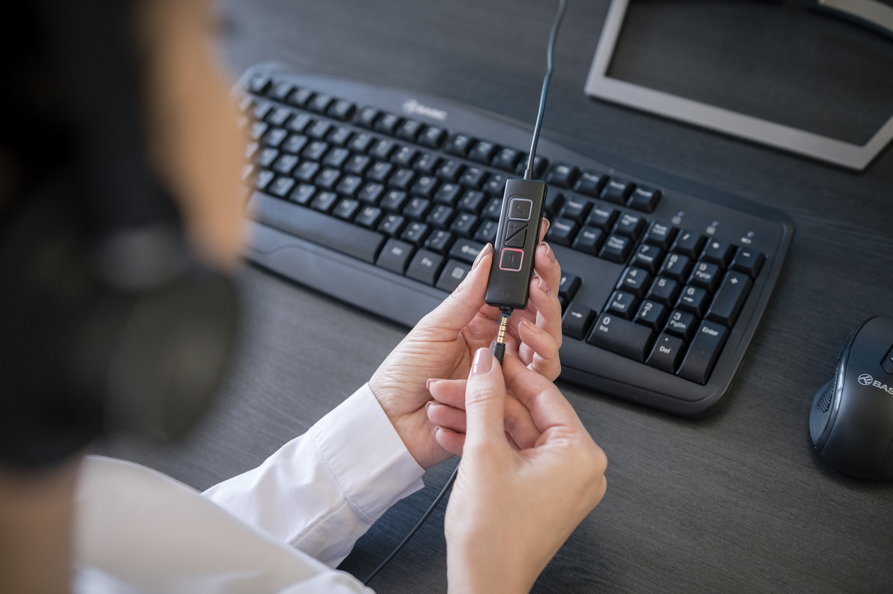 Osoba trzymająca kabel z panelem sterowania, podłączony do klawiatury i myszy.