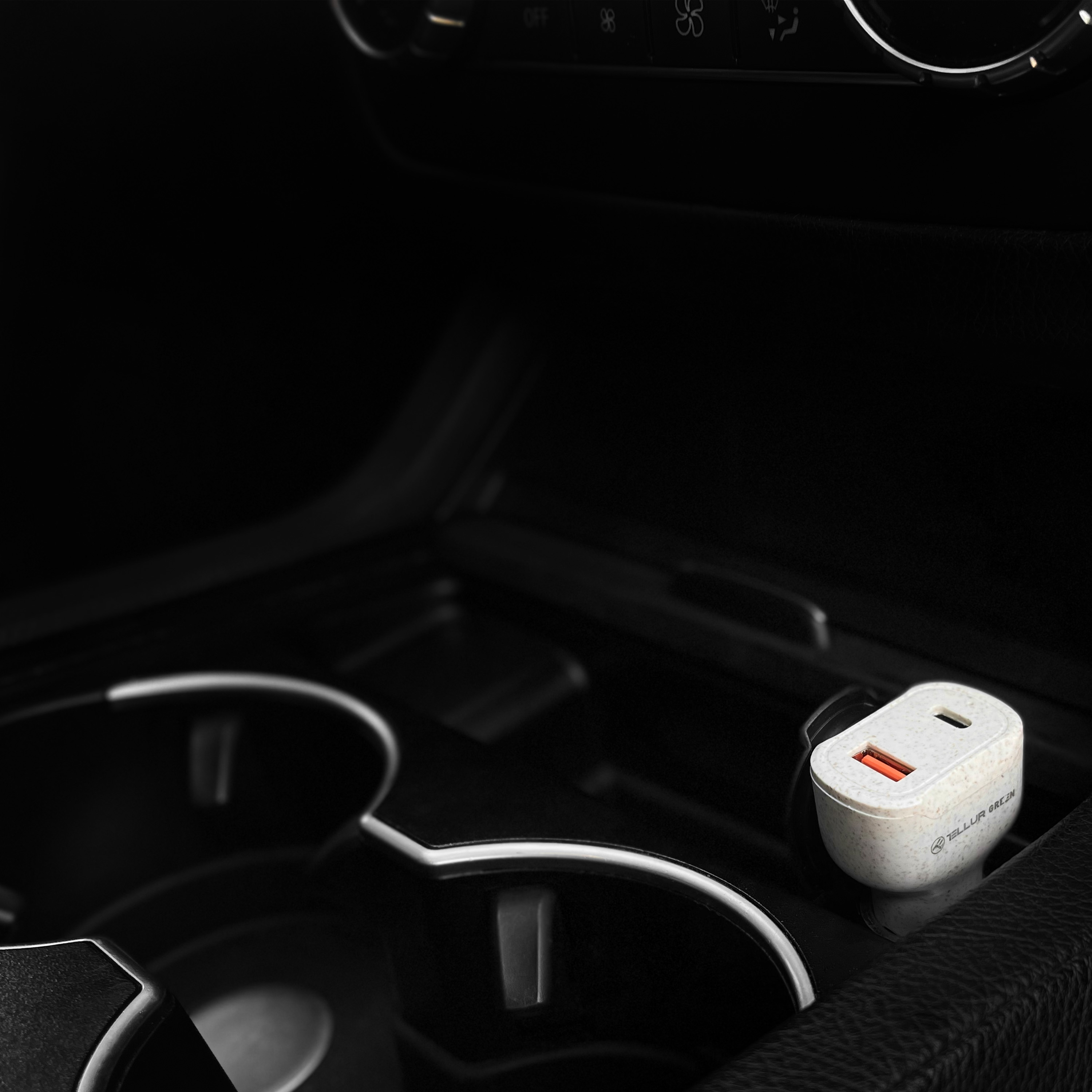 Uchwyt na kubek samochodowy z biało-pomarańczową ładowarką USB. Widoczne czarne wnętrze.