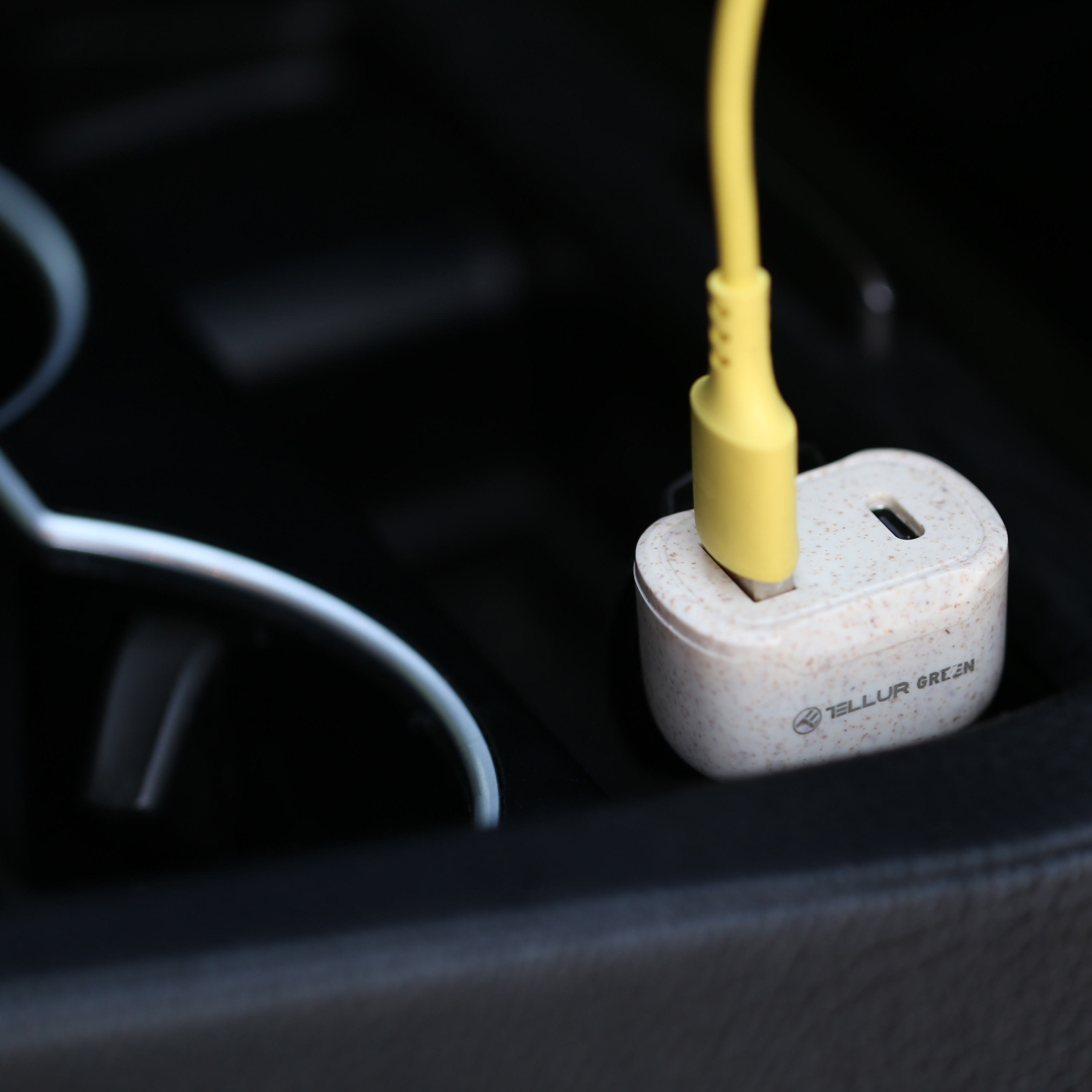 Żółta ładowarka USB-C wpięta w konsolę samochodu.