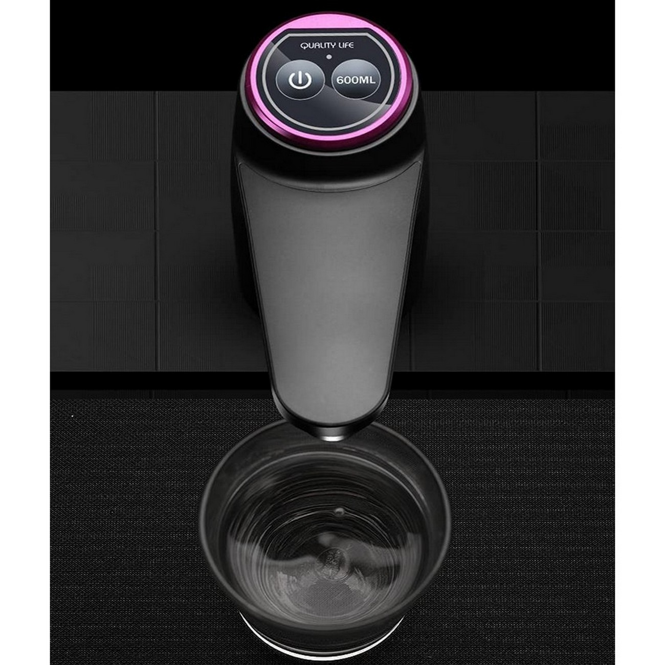 Dispensador de agua negro con tapa rosa. Vaso de agua debajo. Fondo negro.
