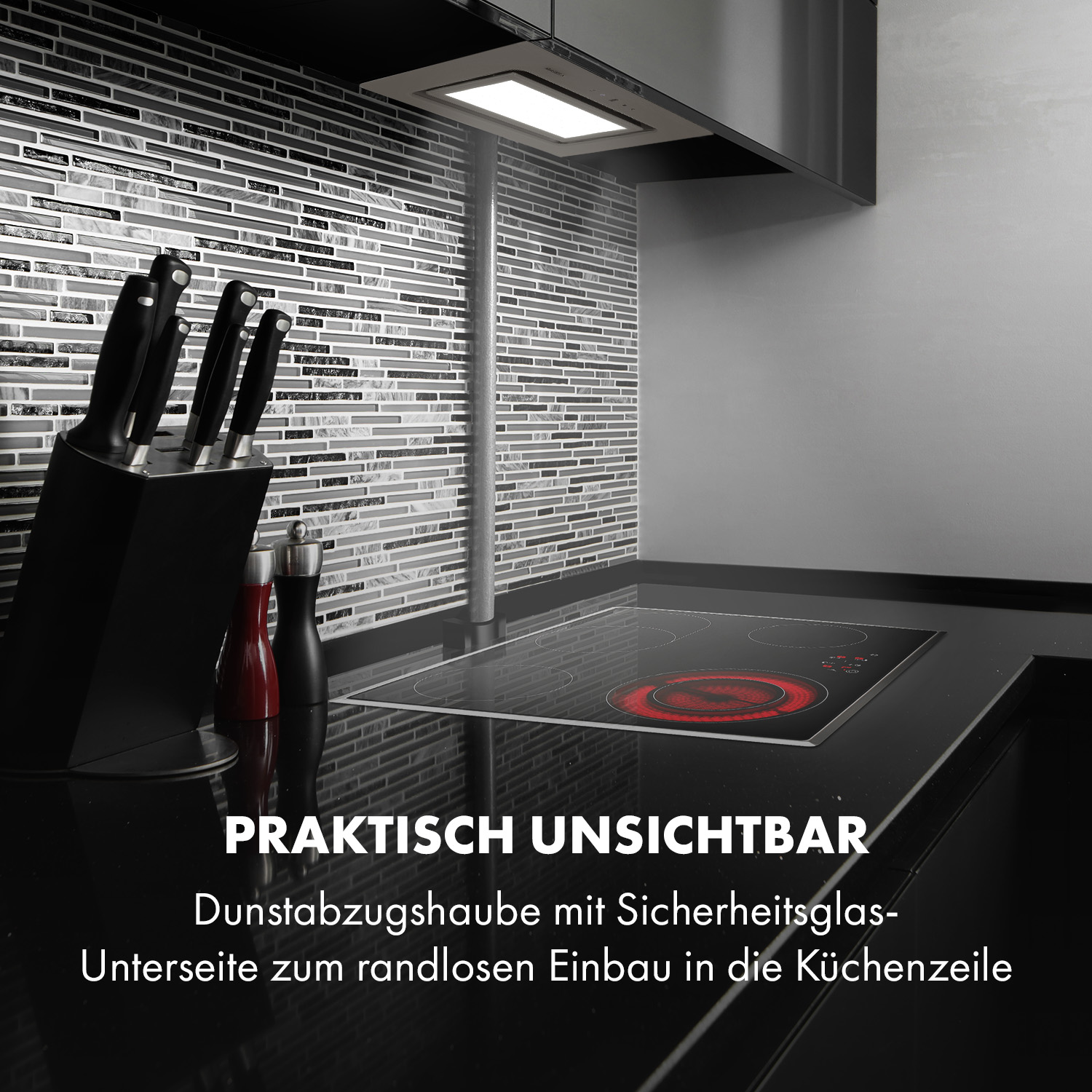 Küchenszene mit schwarzer Arbeitsplatte, Herd, Messern und einem schwarz-weißen Fliesenspiegel.