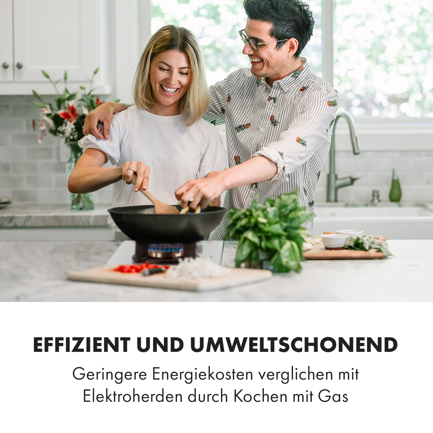 Ein Paar kocht zusammen in einer Küche. Die Frau rührt Essen in einer Pfanne, während der Mann lächelt, Arm um sie.