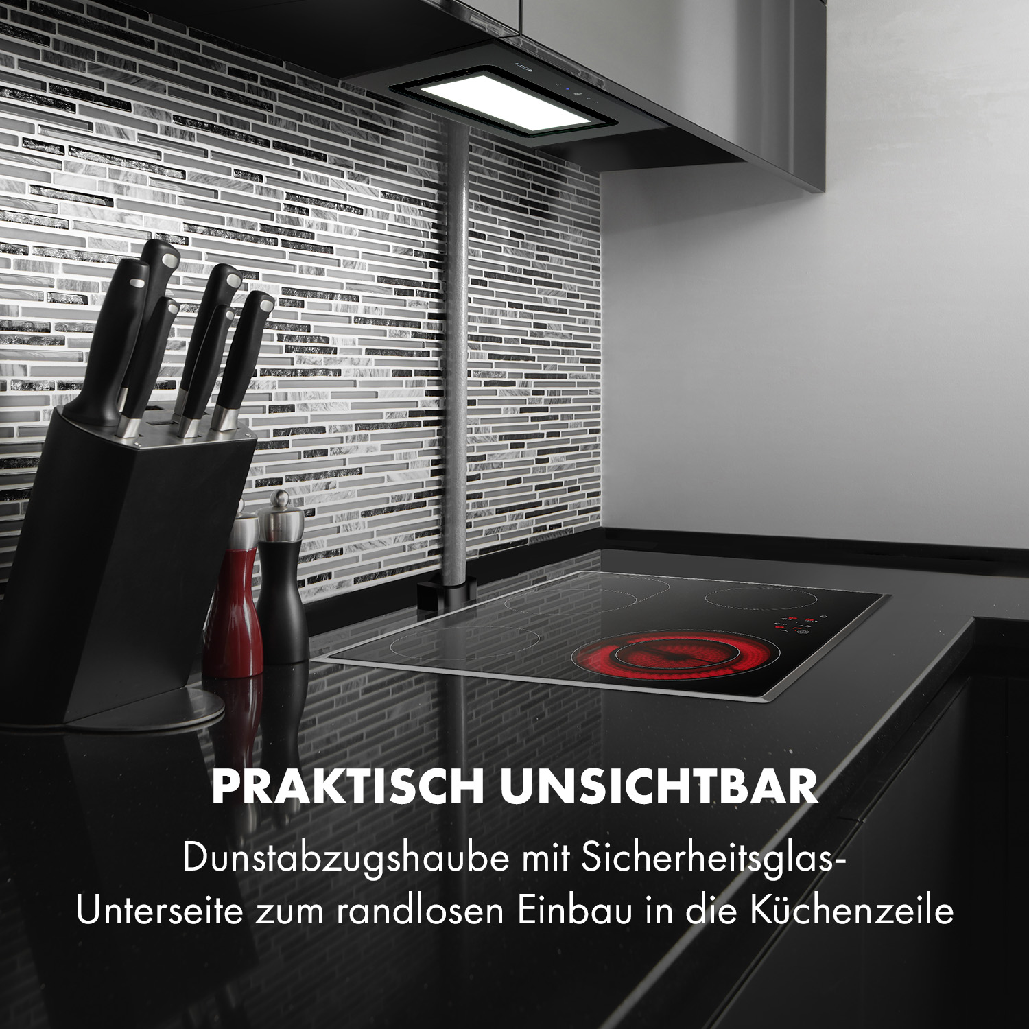 Küchenszene mit schwarzer Arbeitsplatte, Messern und einer modernen Dunstabzugshaube.