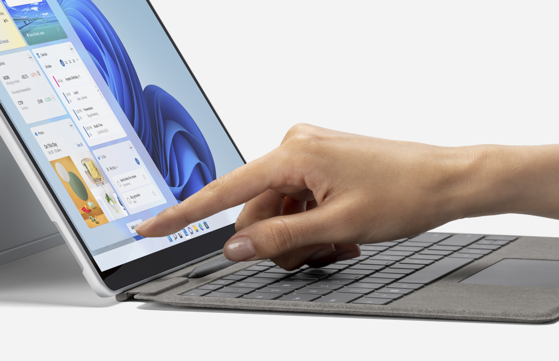 Una mano che usa una penna su uno schermo di un laptop con varie applicazioni aperte.